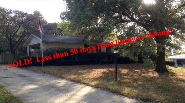 A house with a fence around it and trees in the background.