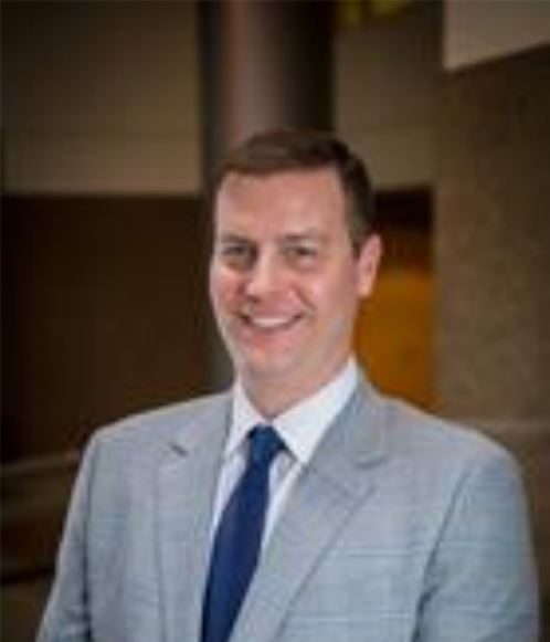 A man in a suit and tie standing next to a building.